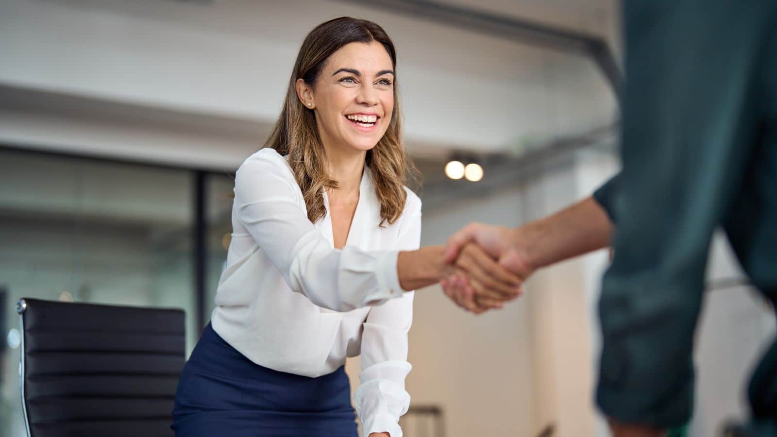 Happy mid aged woman handshaking someone as a sign of respect.