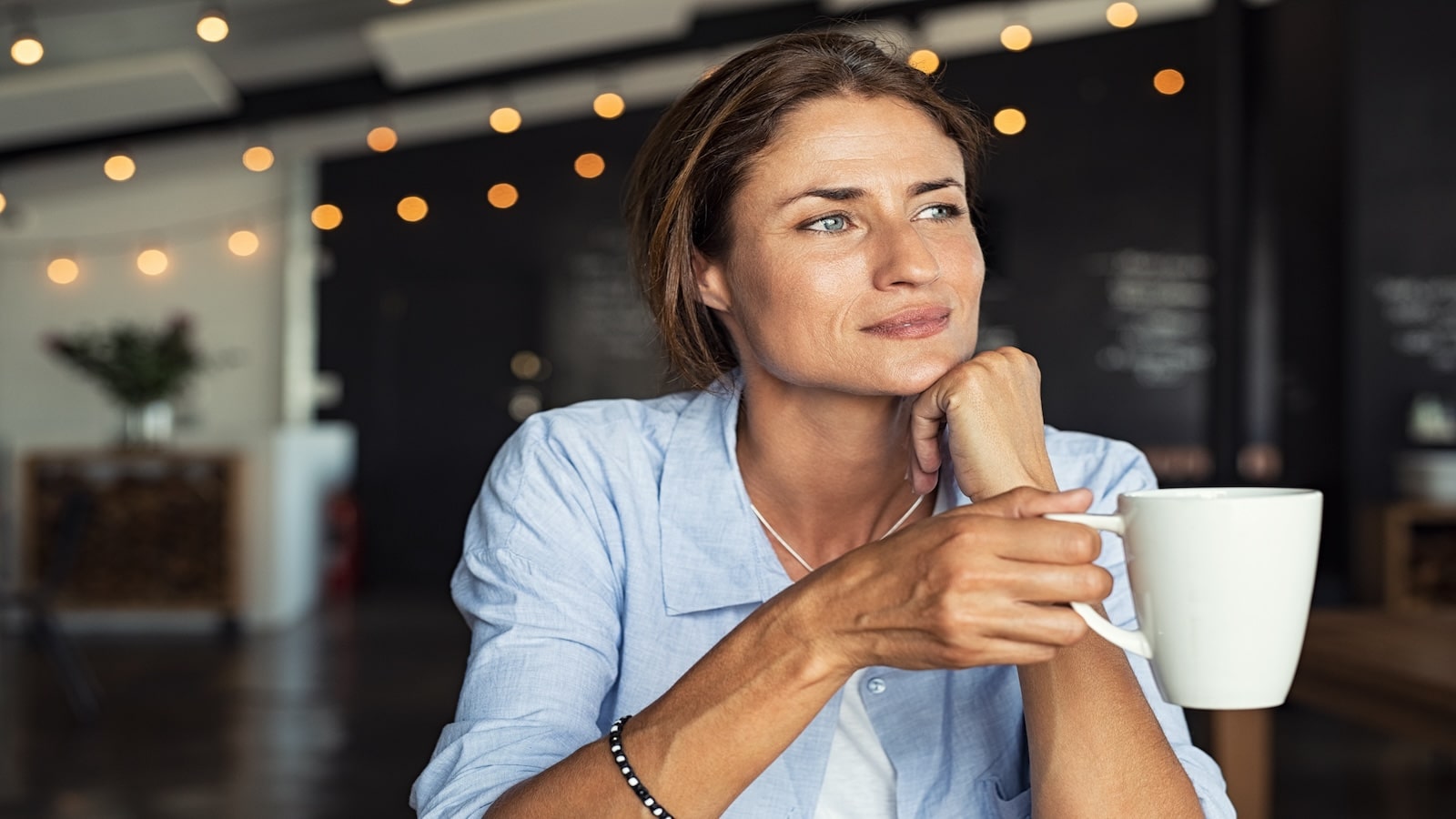 Thoughtful mature woman sitting in cafe relaxing and thinking while drinking coffee.