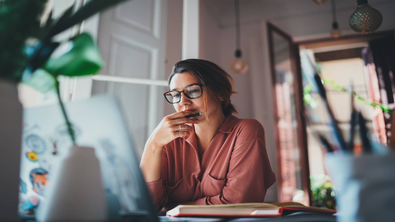 Young woman thinking about something while sitting front open laptop computer.