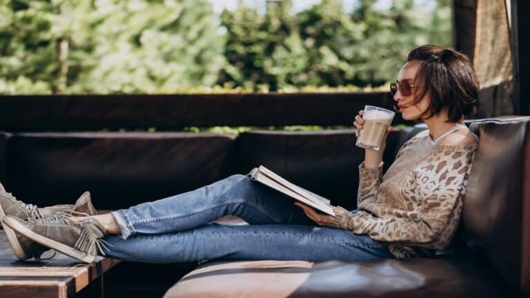 Young woman reading book and drinking coffee.