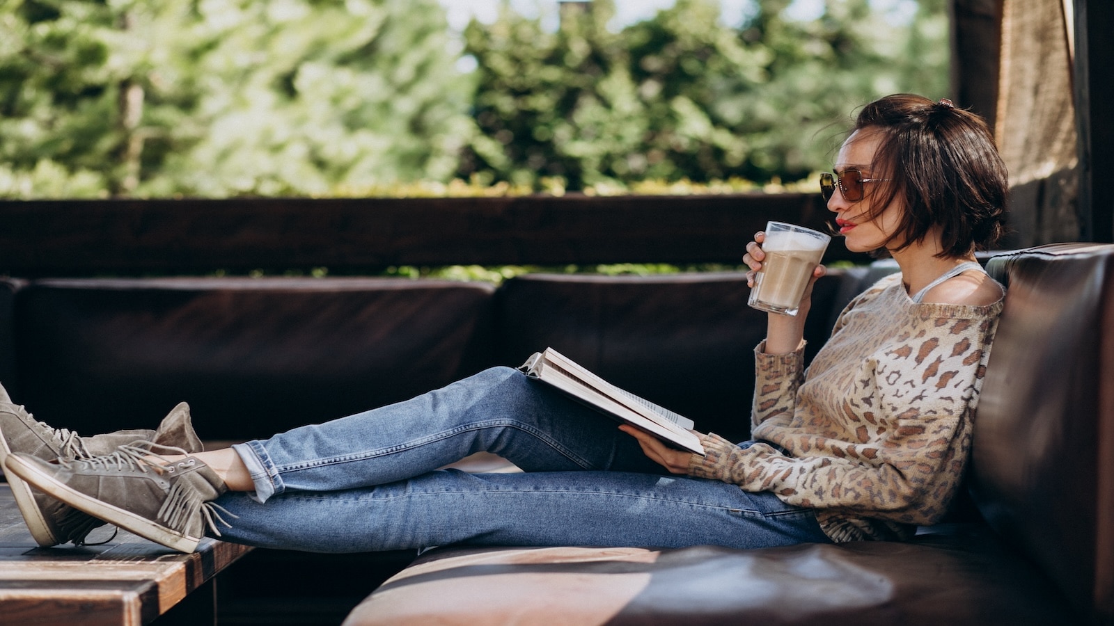 Young woman reading book and drinking coffee.