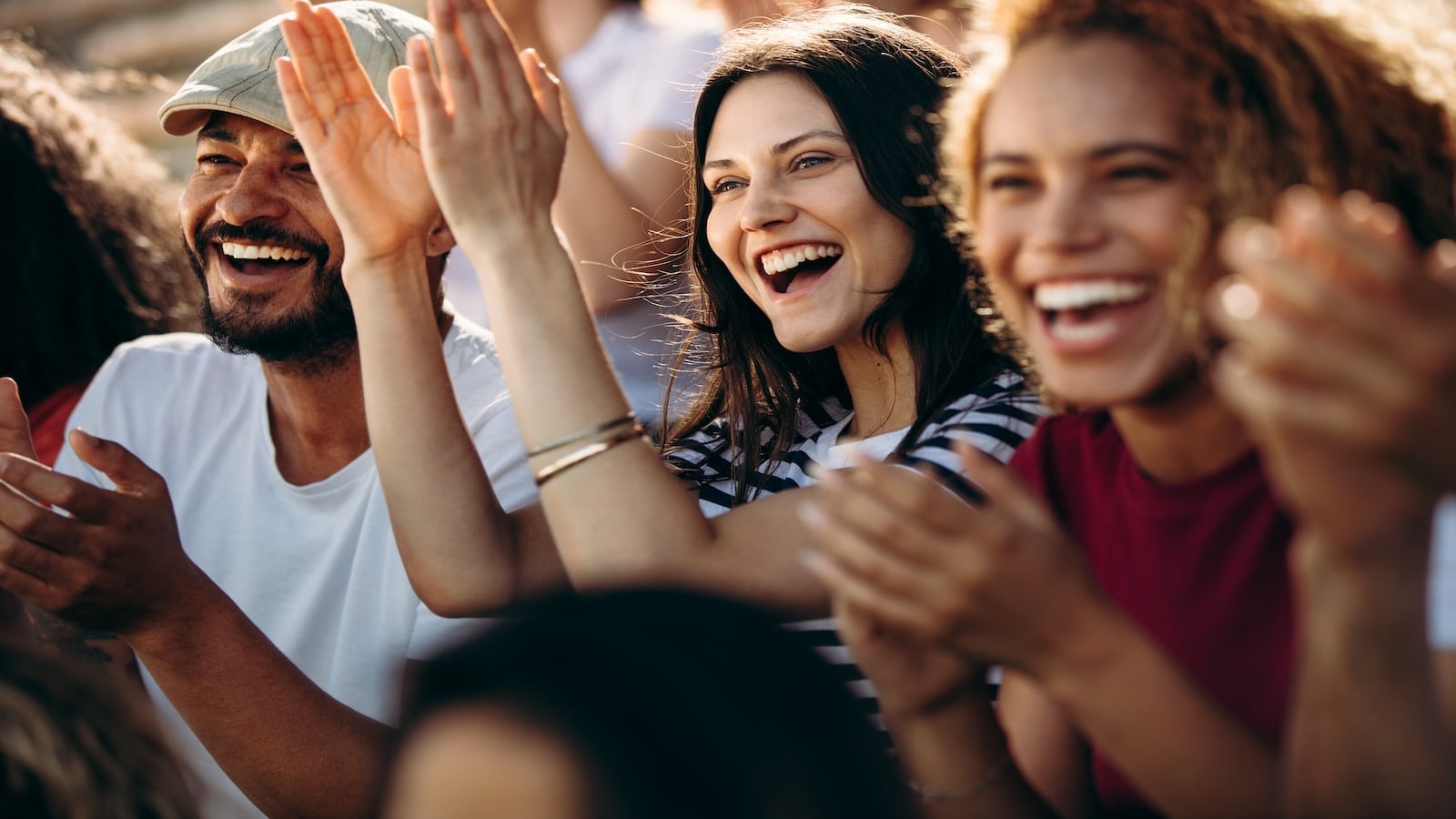 Group of fans/friends watching a sports event in the stands of a stadium.