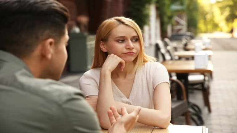 Young woman getting bored during first date with man at outdoor cafe.