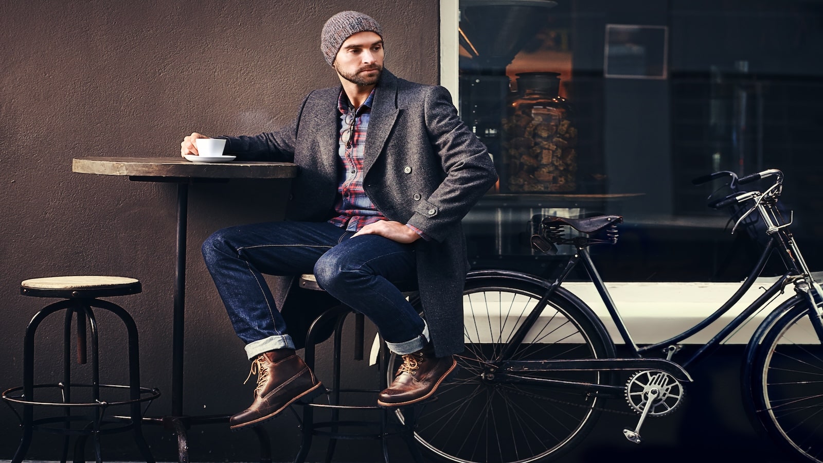 Young man sitting in cafe with coffee and bike.