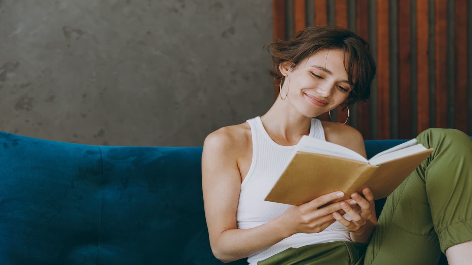 young smart woman reading book relaxing on couch.