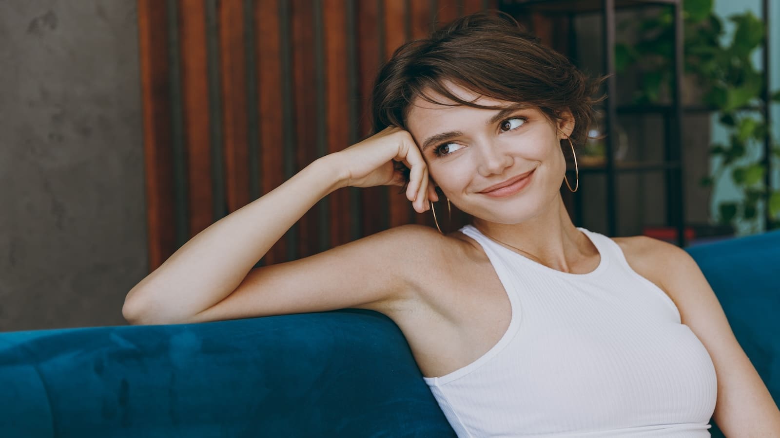 Young woman smiling sitting on couch thinking.