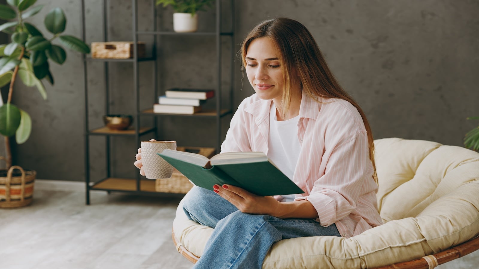 Young woman reading a book sitting in armchair.