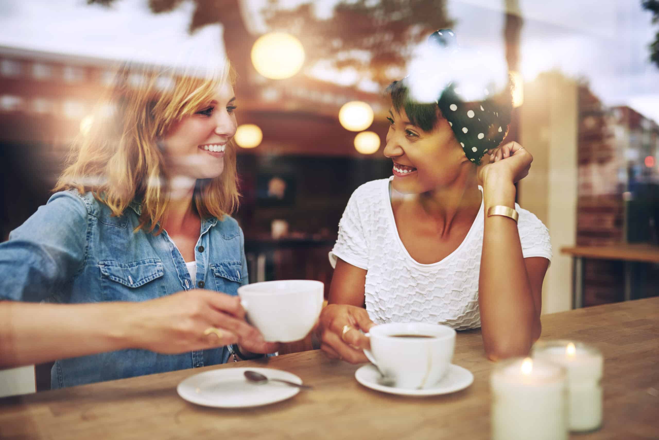 two friends having coffee in a cafe smiling happy.