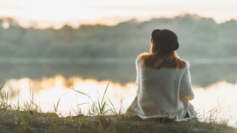 A woman sitting on the river bank in silence.