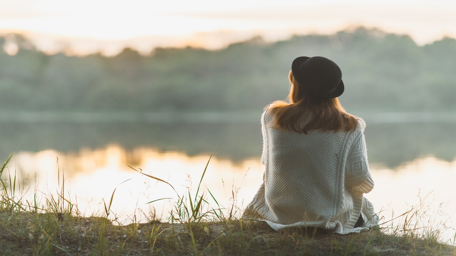 A woman sitting on the river bank in silence.