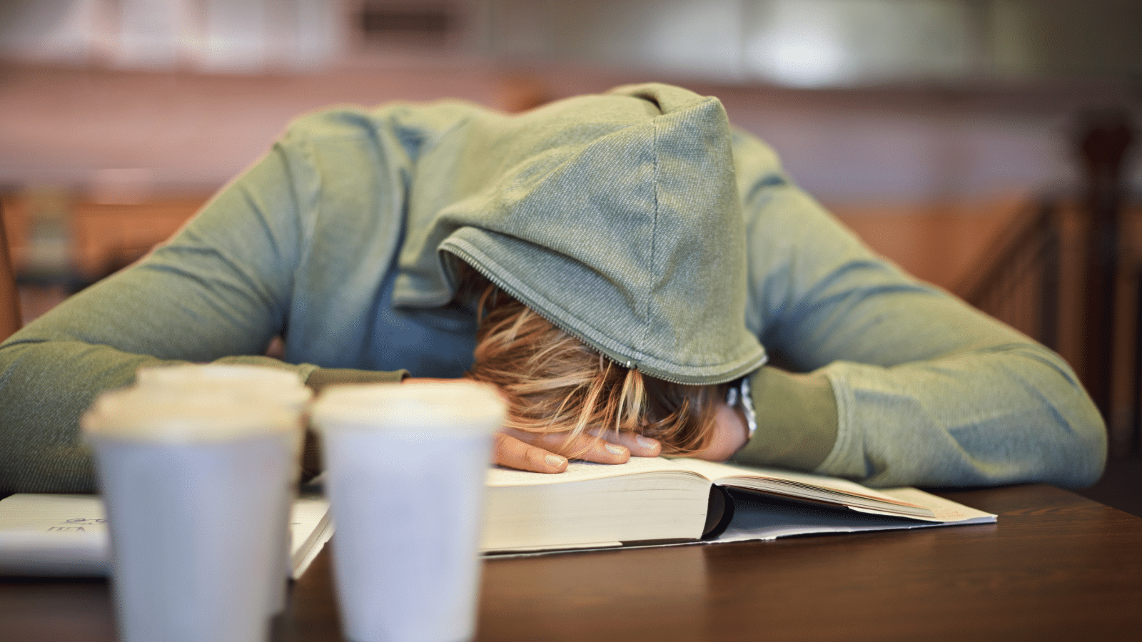 Tired student sleeping in the library with burnout, stress depression or low energy for deadline.
