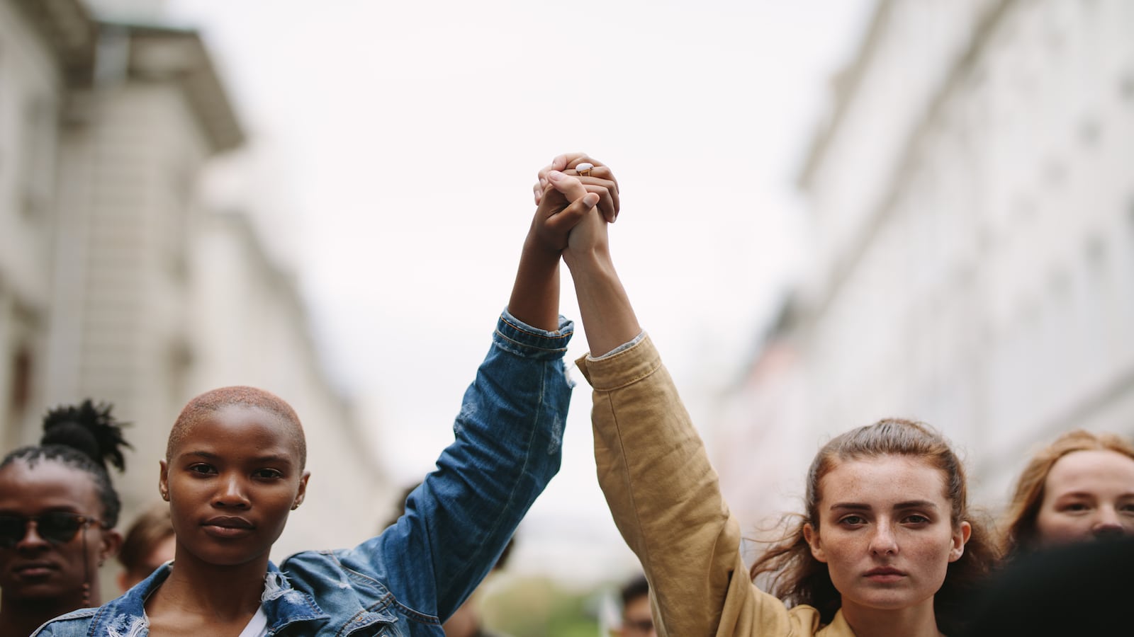 Group of activists with holding hands protesting in the city for equality.