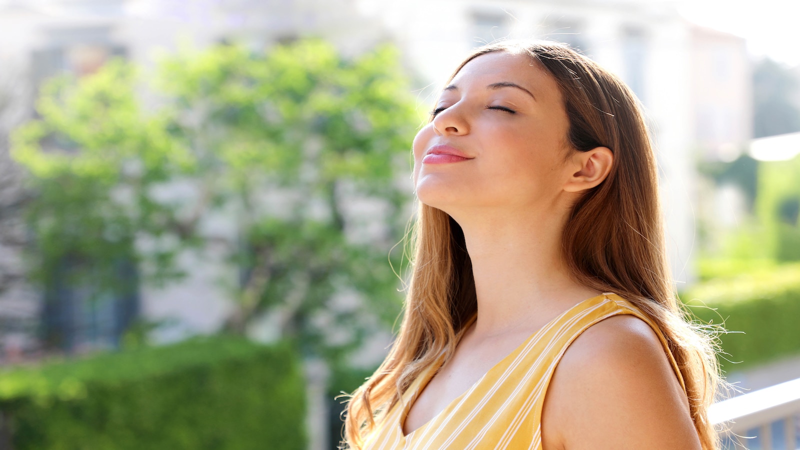 Relaxed woman breathing fresh air on balcony in the morning