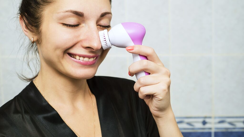 portrait of young woman with perfect skin removing makeup with cleansing brush, device for household Washing and massage Face, applying spa procedures, Female facial skin care, clean the pores of dirt.