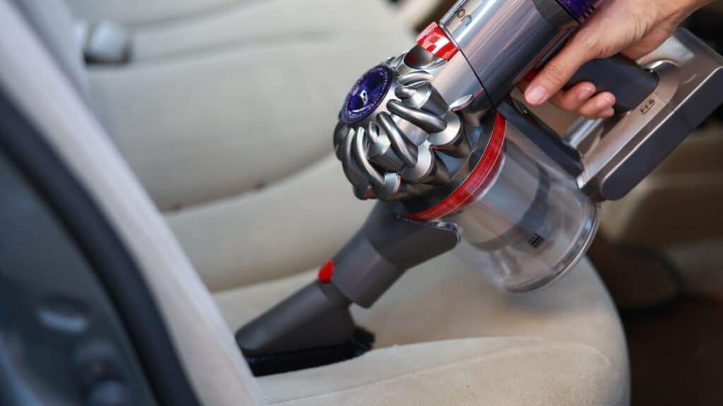 Penang, Malaysia - 19 June 2023: A close-up of a woman using a Dyson V8 Slim Cordless Vacuum to clean her car. Dyson is a British technology company that designs and manufactures household appliances.