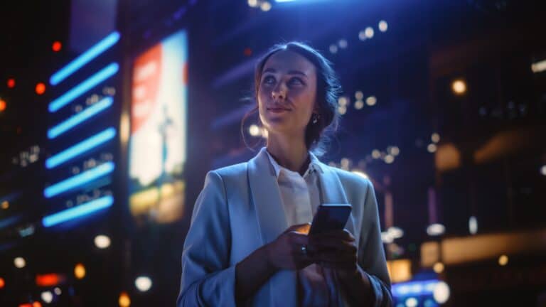 woman in city at night using phone.