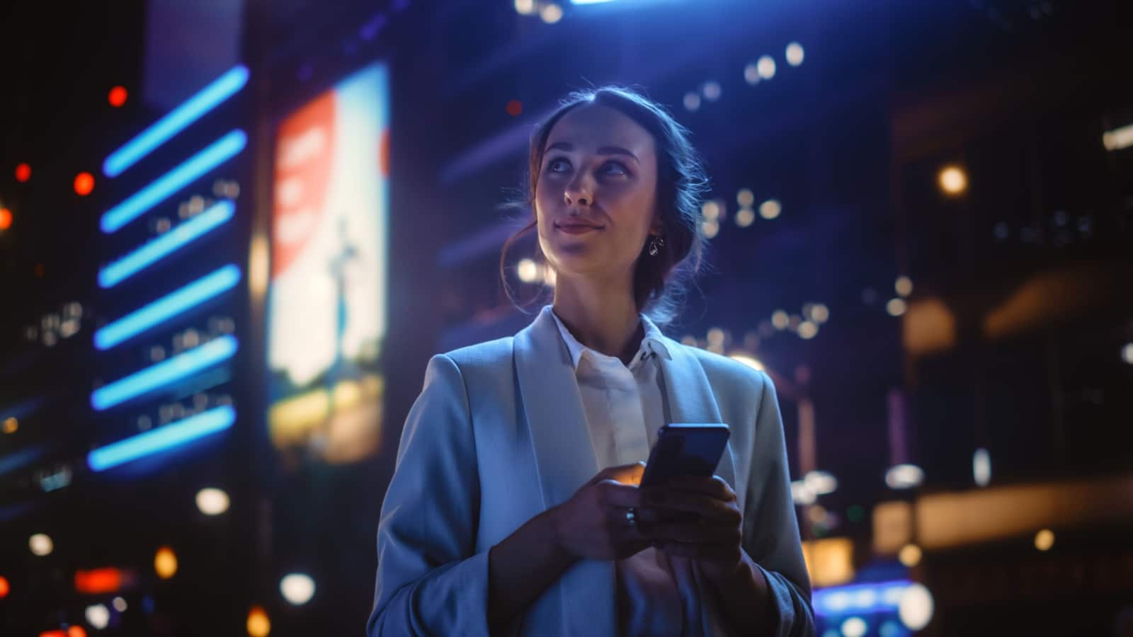 woman in city at night using phone.