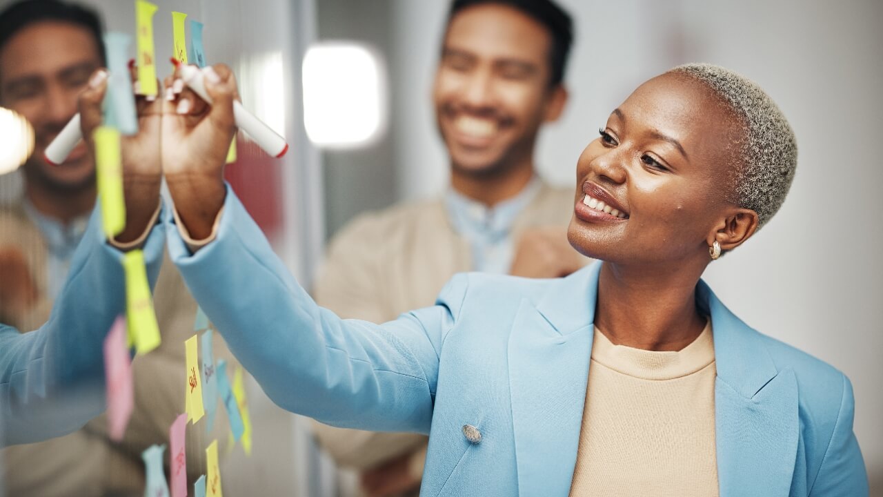 Businesswoman, planning and writing idea in meeting, calendar or agenda, sticky note or innovation. Idea, brainstorming and black woman leader with goal or problem solving, teamwork or solution