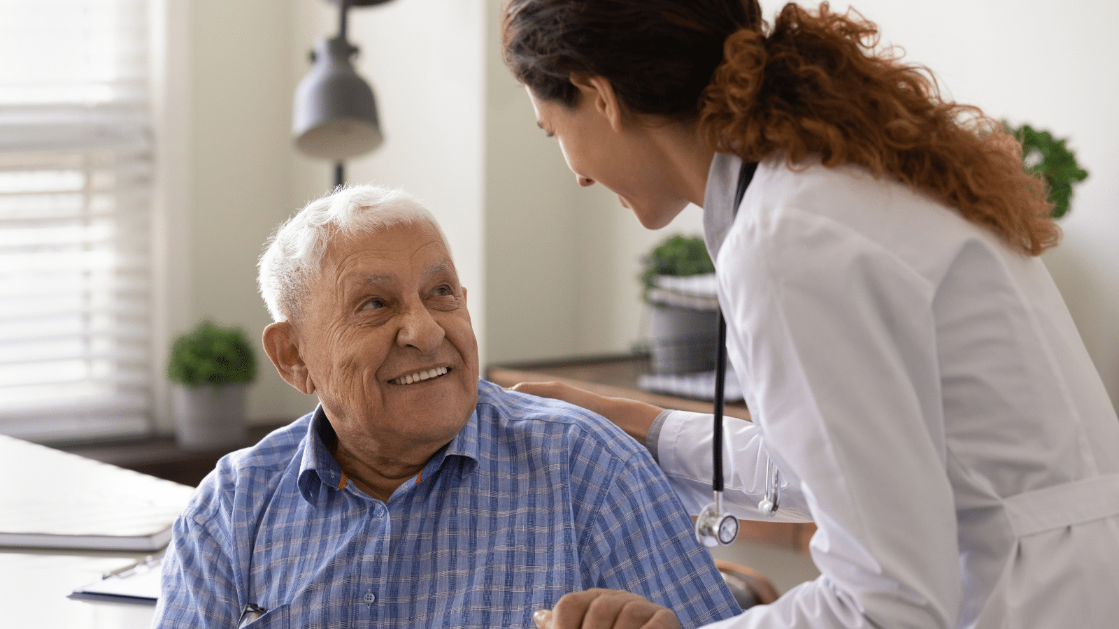 Close up caring nurse holding smiling patient hand at meeting in hospital, comforting and supporting senior man.