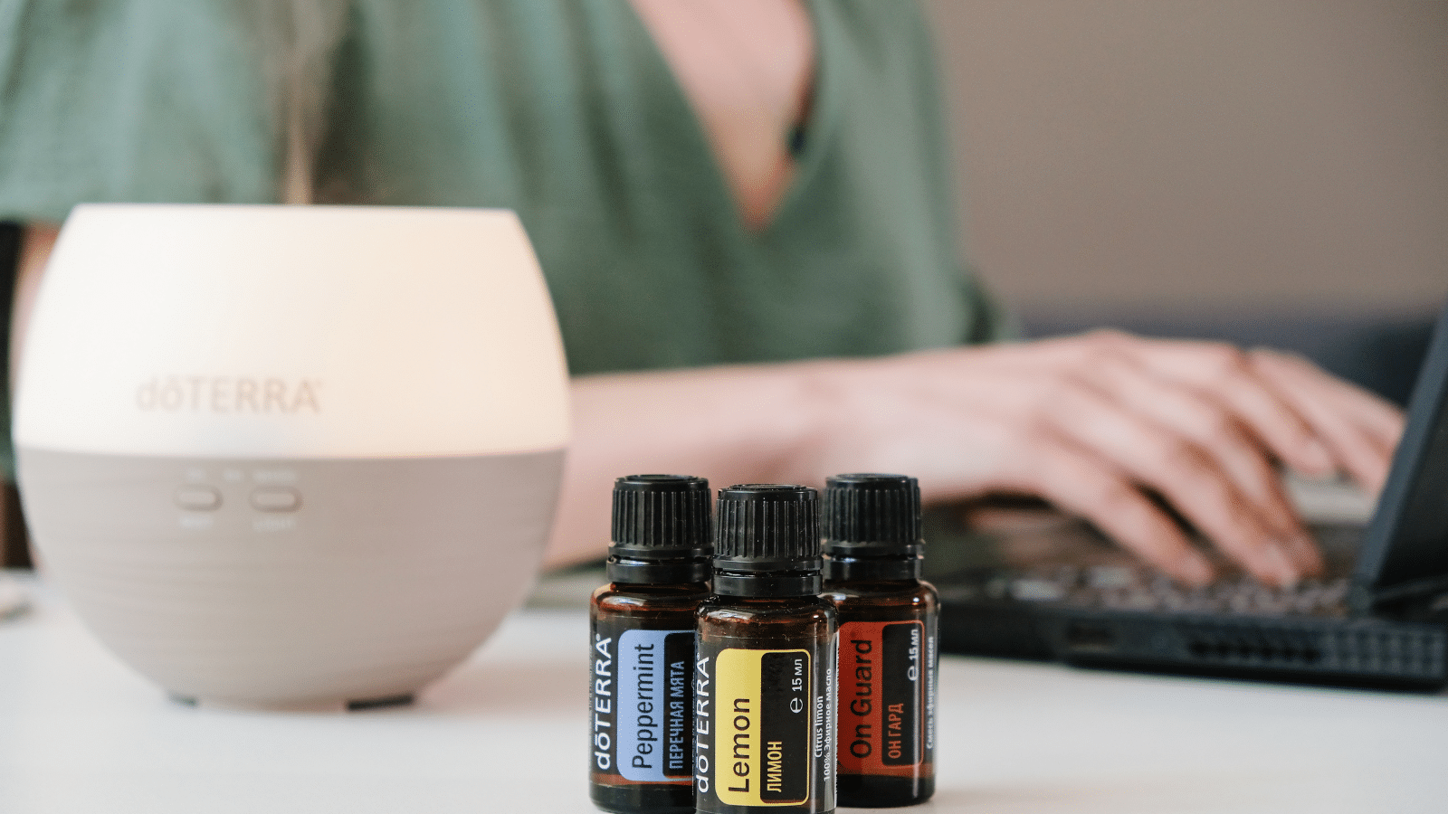 Woman working on laptop and using Doterra oil diffuser, aromatherapy for office. Lemon, Peppermint and Onguard.