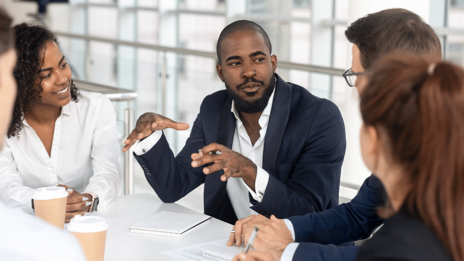 Millennial employees gathered in boardroom for training, employees using active listening.