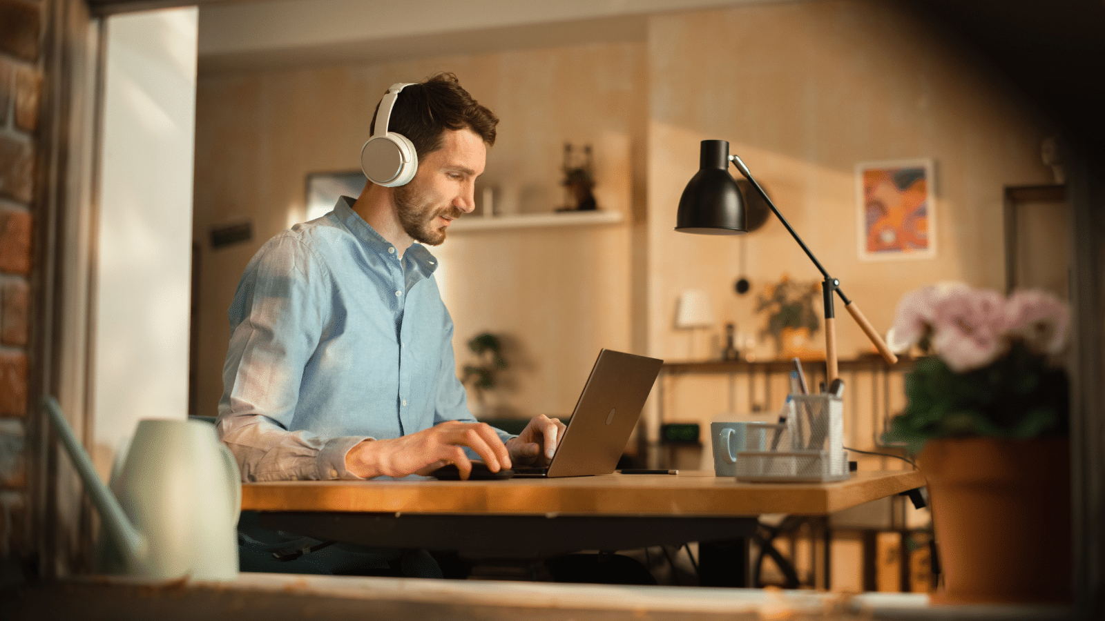 Professional ma wearing headphones listening to music while and working on laptop.