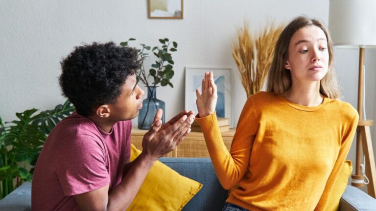 Black man begging for forgiveness and Caucasian woman turning him down in a house