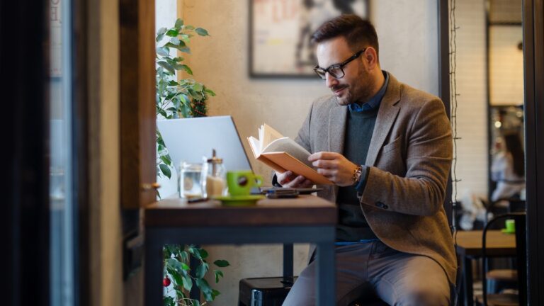 Businessman Reading Book while Sitting in Cafe