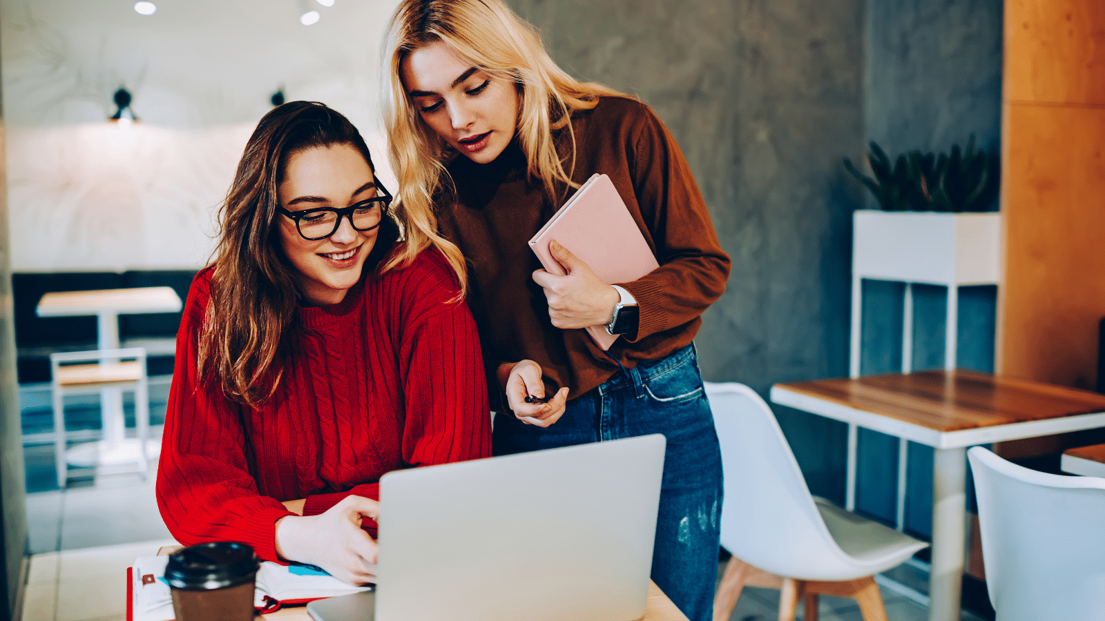 Female students or coworkers working on a project together using teamwork.