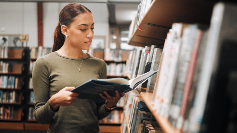Woman reading book in a library for education, studying and research in school, university or college campus.