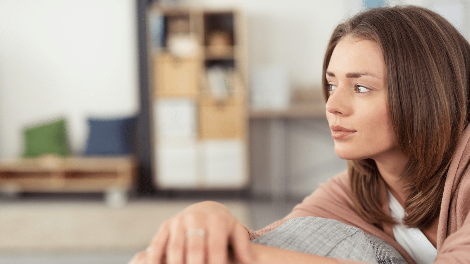 Close up woman sitting on a couch looking into the distance.