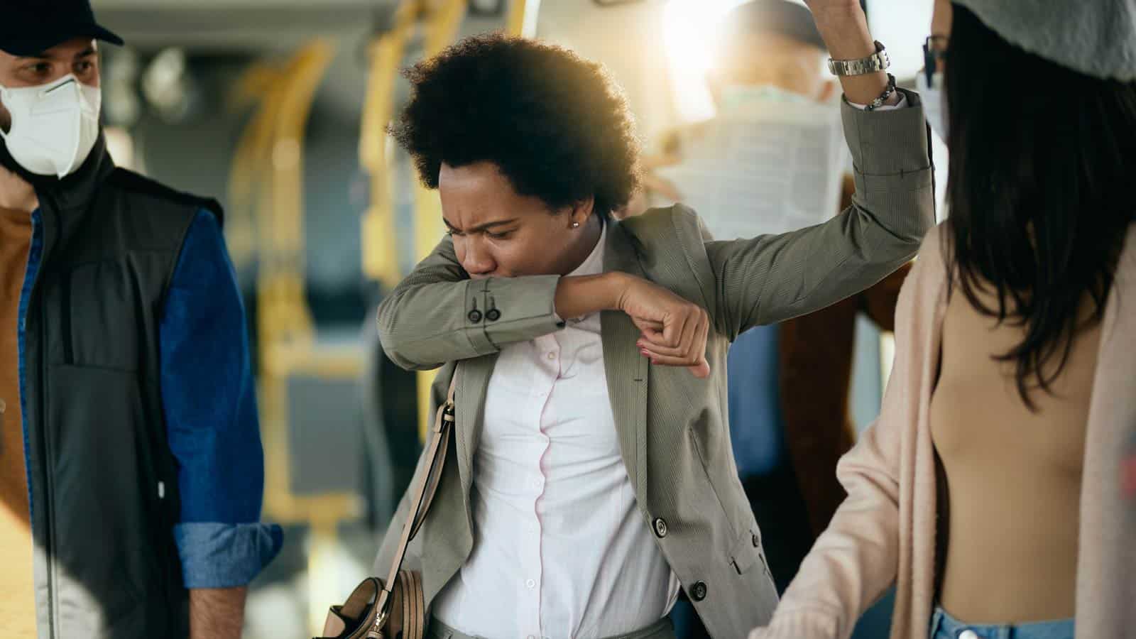 woman sneezing on train in crowd