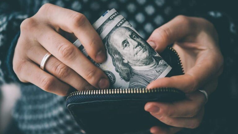 Person putting dollar bills in a wallet