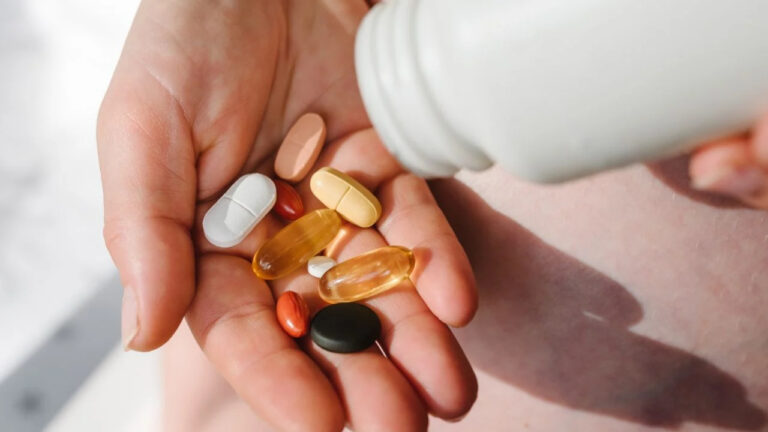 Closeup photo of supplements with a white bottle. Pregnant woman take omega 3, multivitamins, vitamins B, C, D, collagen tablets, probiotics, iron capsule. Girl hold vitamins daily. Top view