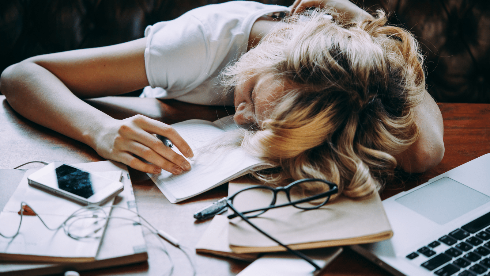 A tired girl sleeping on her table while doing her school homework, procrastinating.