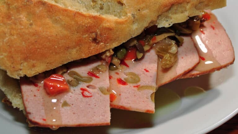 An olive loaf sandwich prepared with olive bread, olive loaf, olive topping, and olive oil