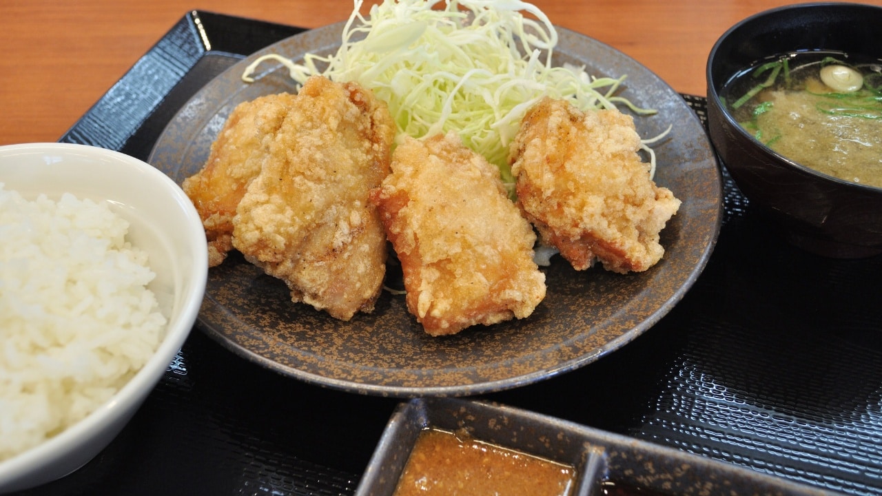 Plated Chicken Karaage with sauces and miso soup next to white rice.