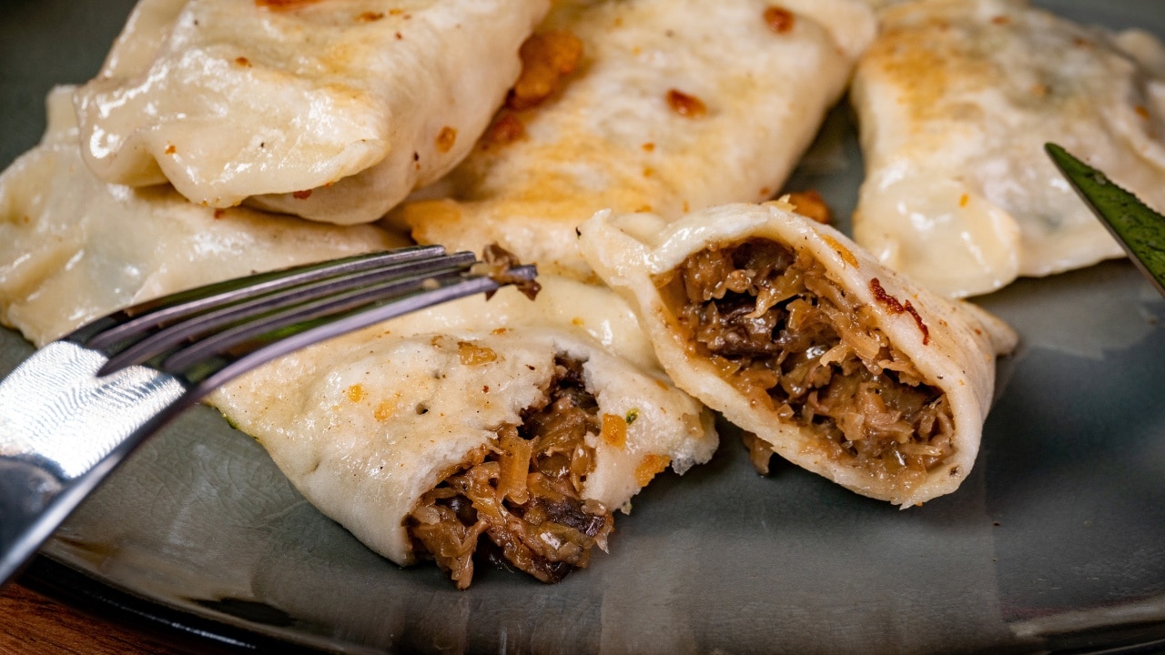 Fried dumplings (pierogi) stuffed with cabbage and mushrooms sprinkled with greaves.