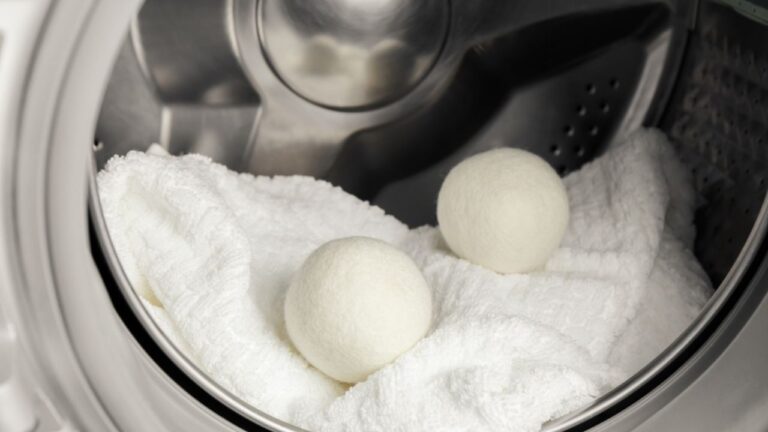 Using wool dryer balls for more soft clothes while tumble drying in washing machine concept. Discharge static electricity and shorten drying time, save energy.