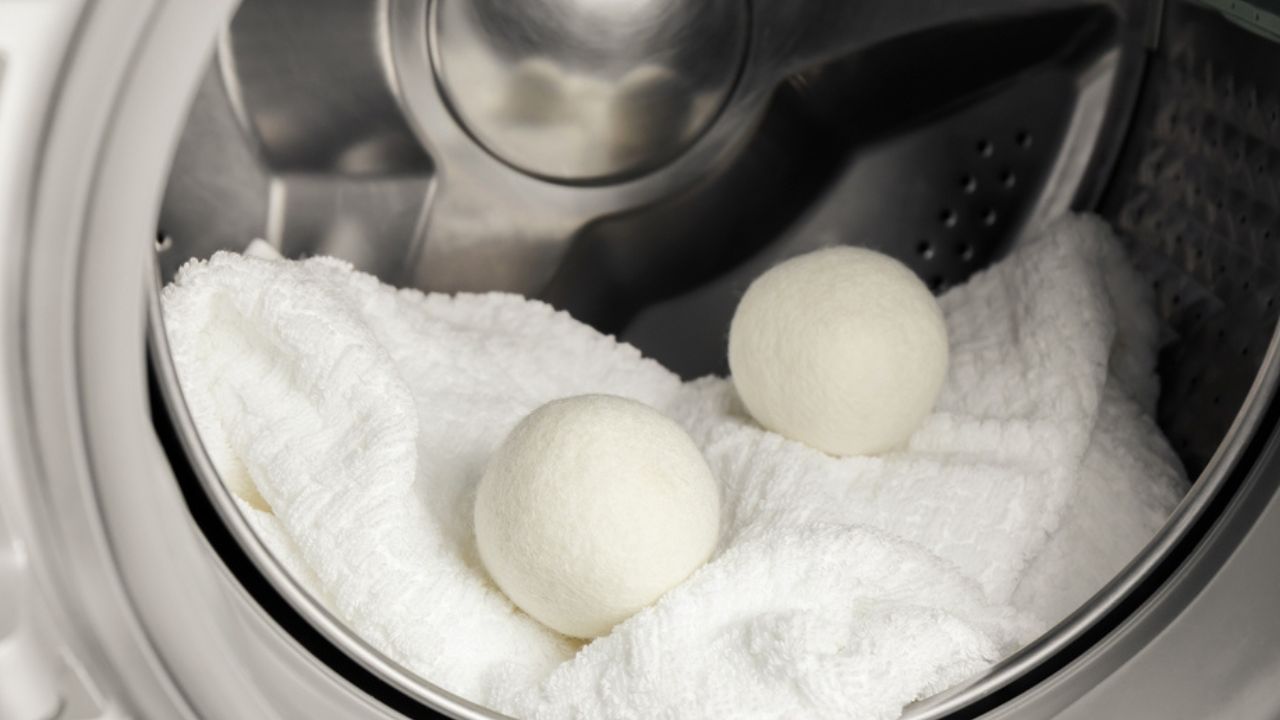 Using wool dryer balls for more soft clothes while tumble drying in washing machine concept. Discharge static electricity and shorten drying time, save energy.