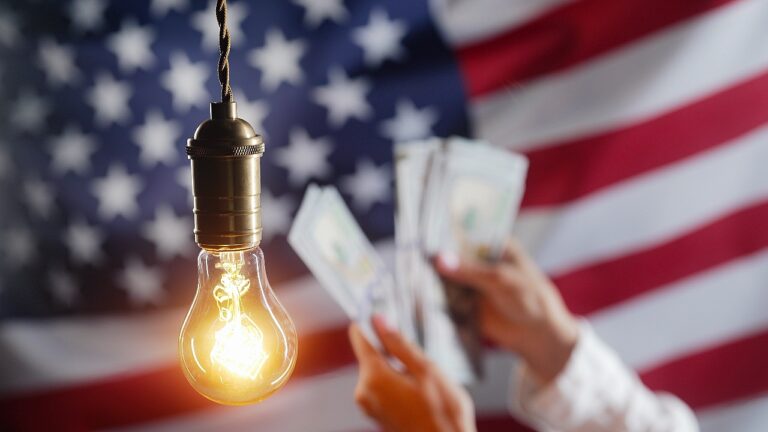 Glowing Edison light bulb on american USA flag background. Woman counting money