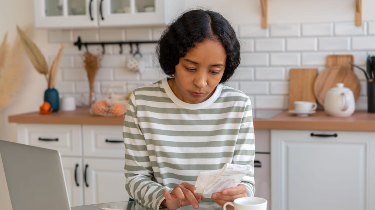 woman laptop calculator bills kitchen worried finances