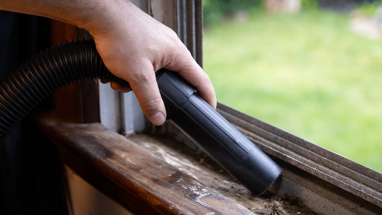 Cleaning debris out of window ledge and grooves with vacuum.