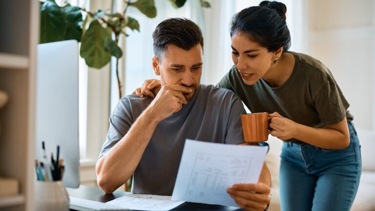 Pensive man and his wife going through bills while planning their home finances at home.