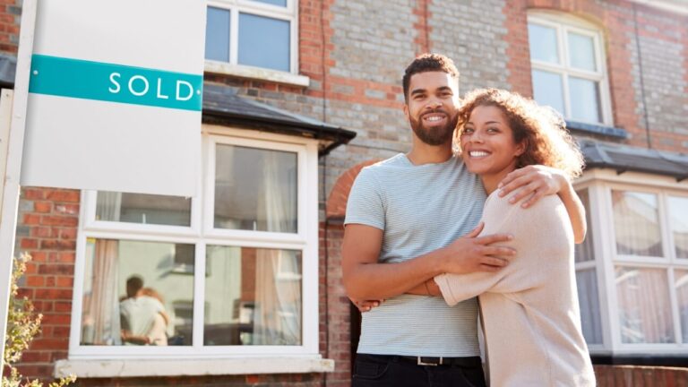 Couple man woman standing in front a house with a sold sign