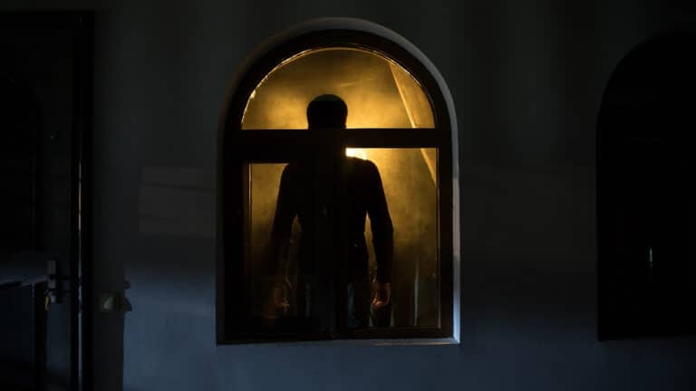 Silhouette of a ghost looking out of a window at night