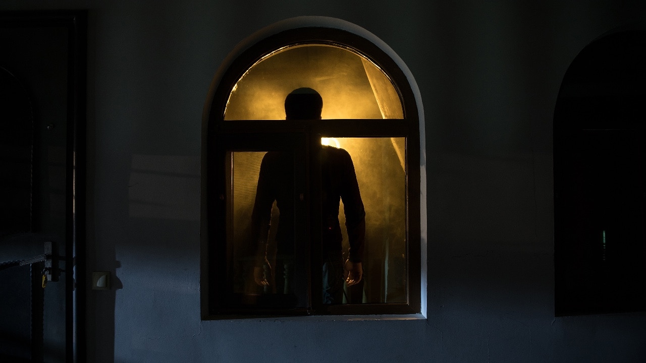 Silhouette of a ghost looking out of a window at night