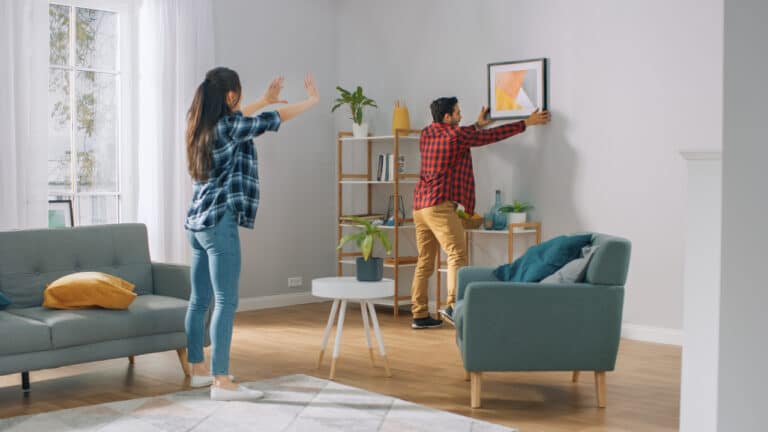 a man and woman decorating or redecorating by hanging a picture