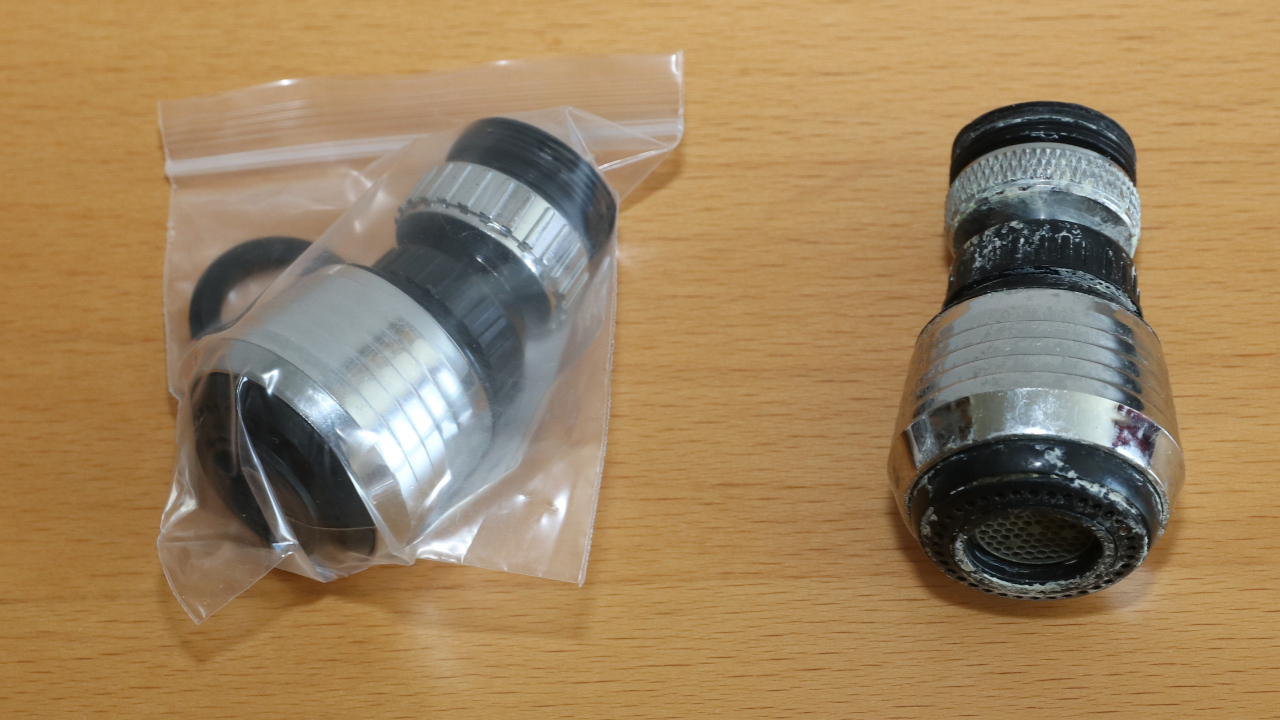 Two faucet aerators: new one in plastic bag and an old one with broken threading.