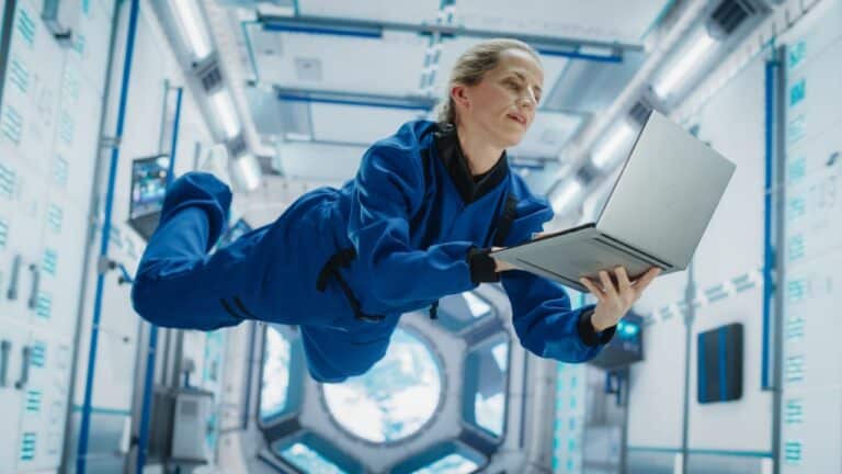 Female Astronaut Using a Laptop in Space Inside a Spacecraft.
